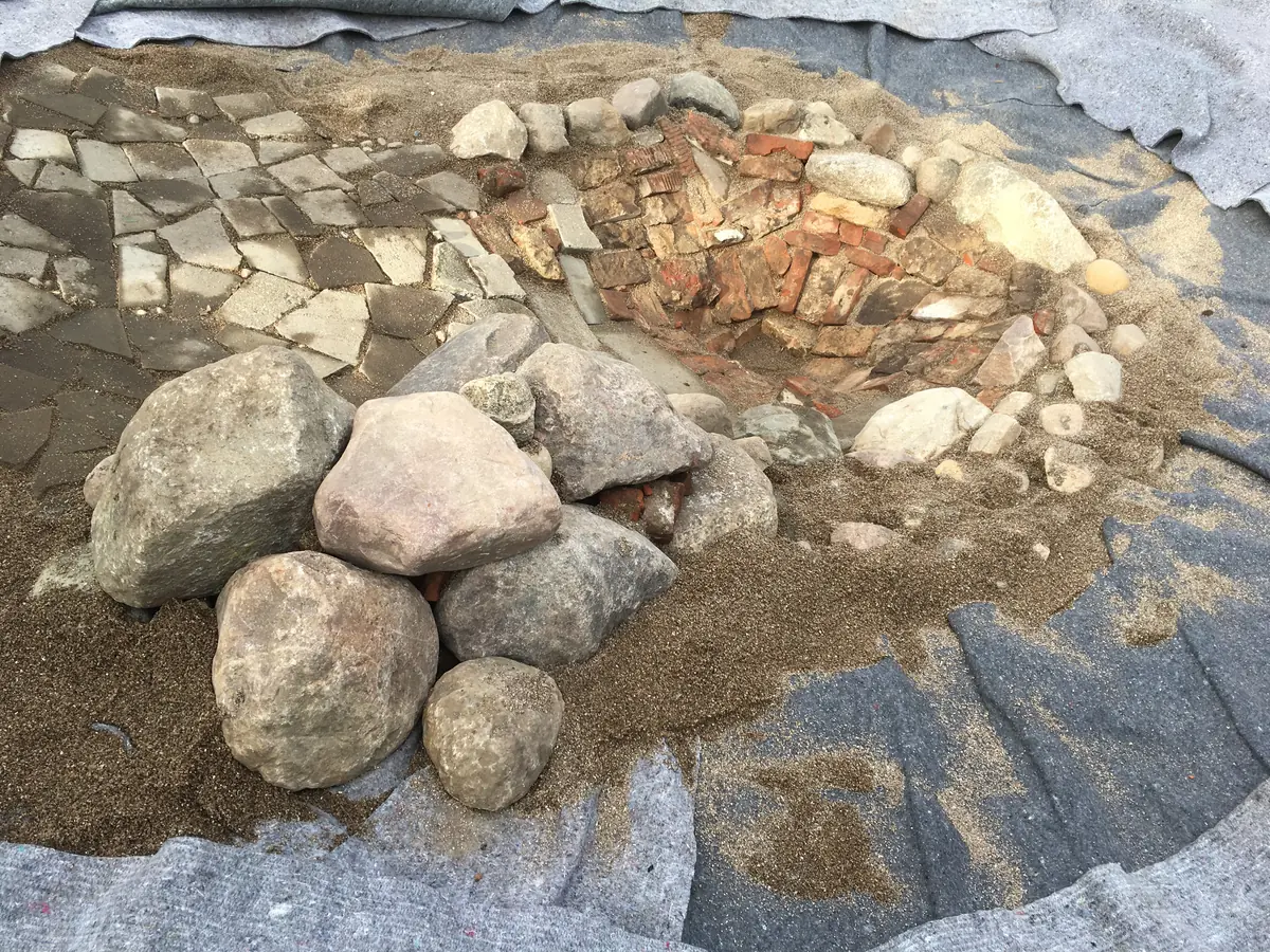 Mit Sand, großen Steinbrocken und alten Plattenresten natürlich ausgekleidet
