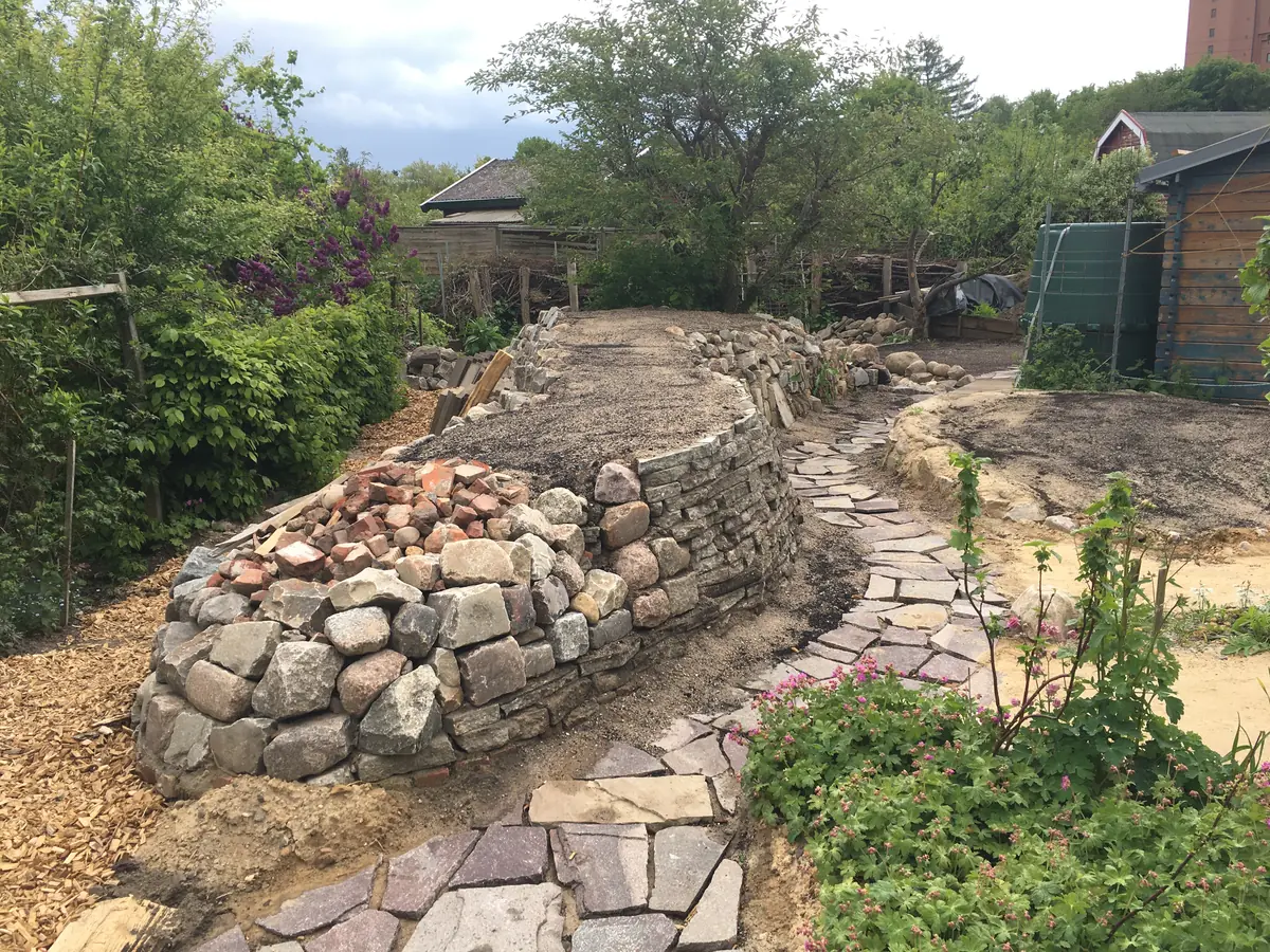 Perspektive vom Kopfende – ein geschwungener Mosaikpfad säumt die Trockenmauer